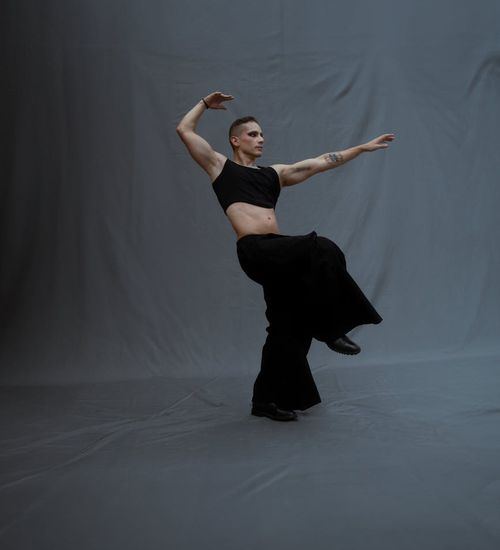 Man performing a controlled strength exercise in a minimalist studio.